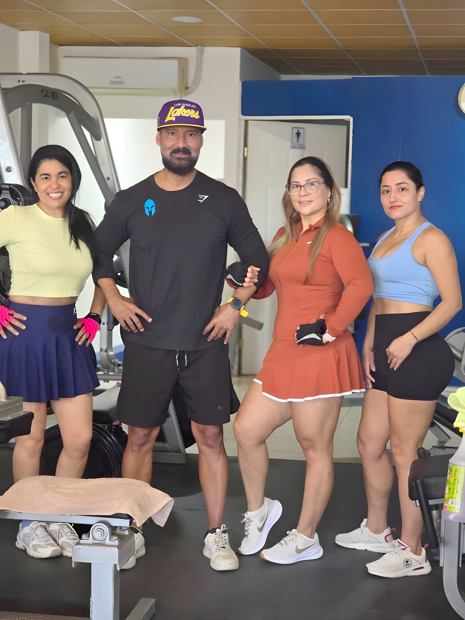 Un entrenador de ENERGYM posa en la sala junto a tres socias