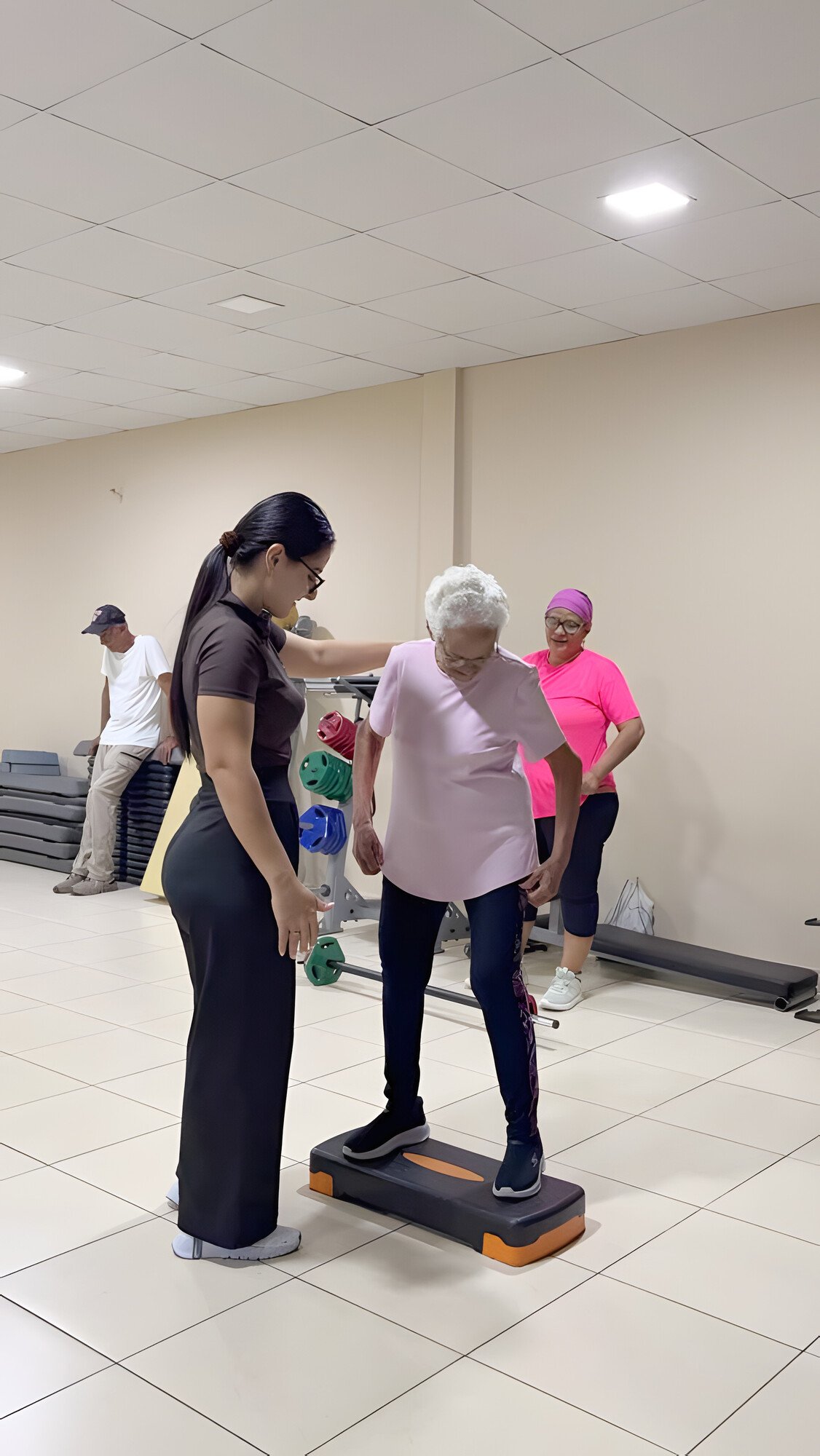 Una mujer acompaña a una participante que practica equilibrio sobre un step