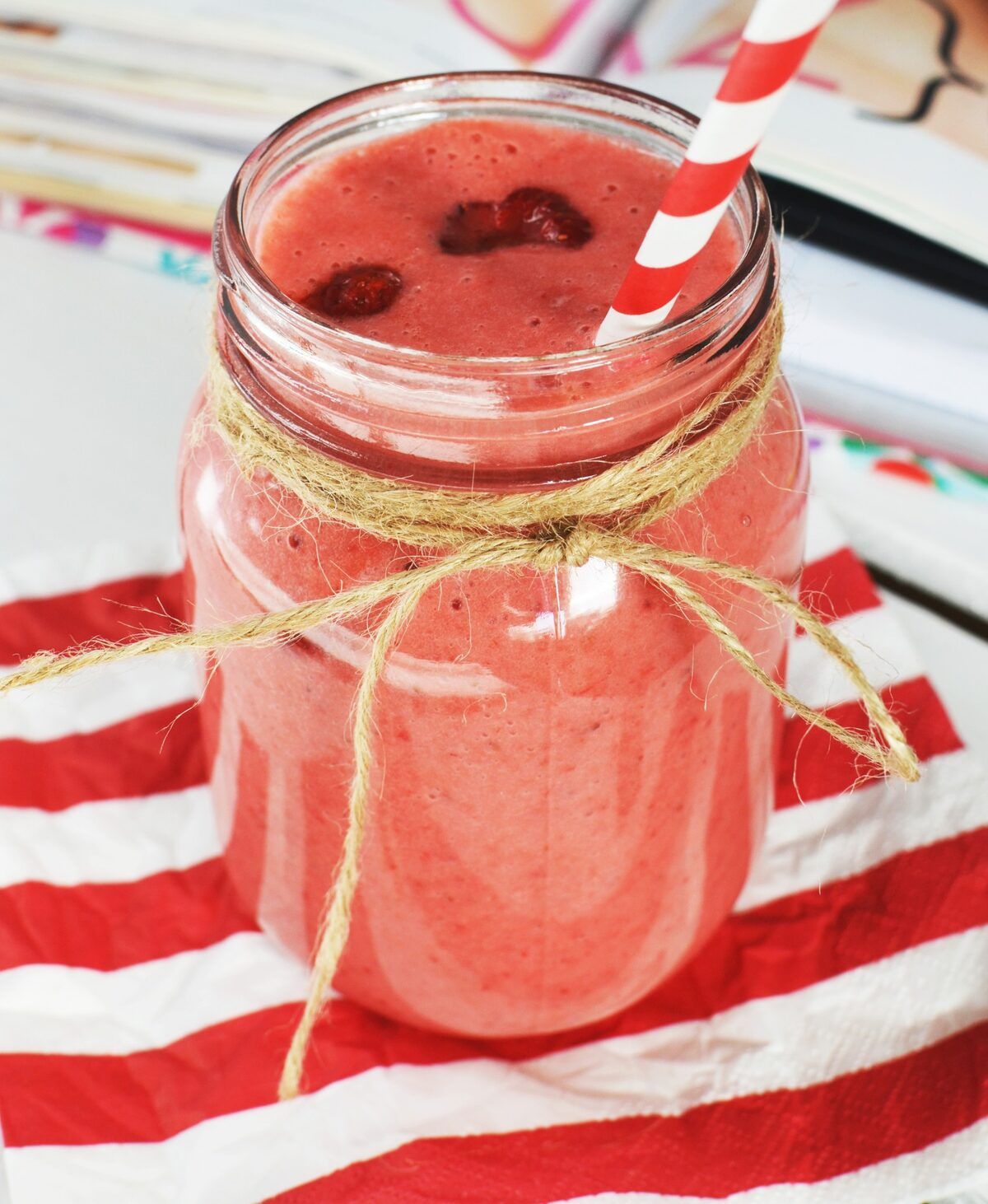 Batido rojo de frutas en un frasco de vidrio con pajilla